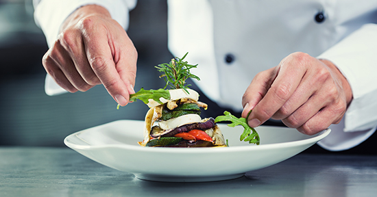 chef arranges vegetable dish on plate