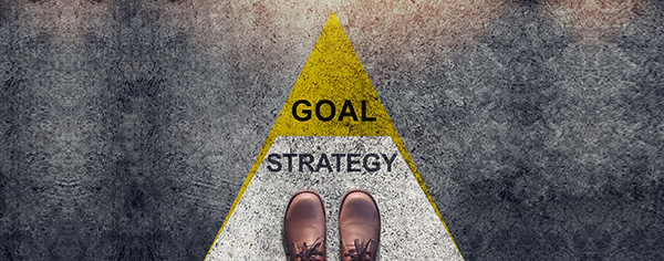 image looking down at feet on a road that says strategy and goal with an arrow pointing forward