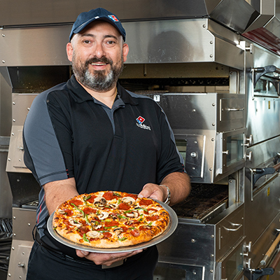 Photo of Gus Garcia holding a freshly baked domino's pizza