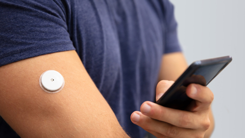 photo of man checking glucose level on a wearable monitor