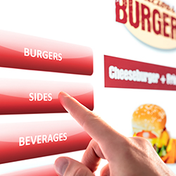 customer ordering fast food through self-service kiosk in restaurant