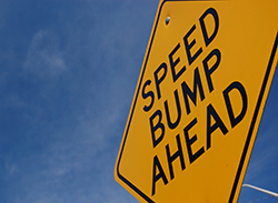 Yellow road sign reading speed bump ahead