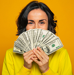 businesswoman on yellow background holding fanned-out money