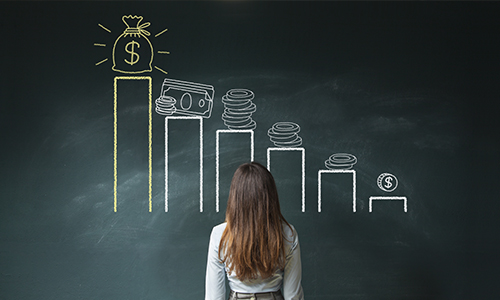 businesswoman looking at chalkboard with graph of increasing money